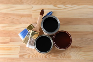 Can with different wood stains and brushes on wooden surface, flat lay