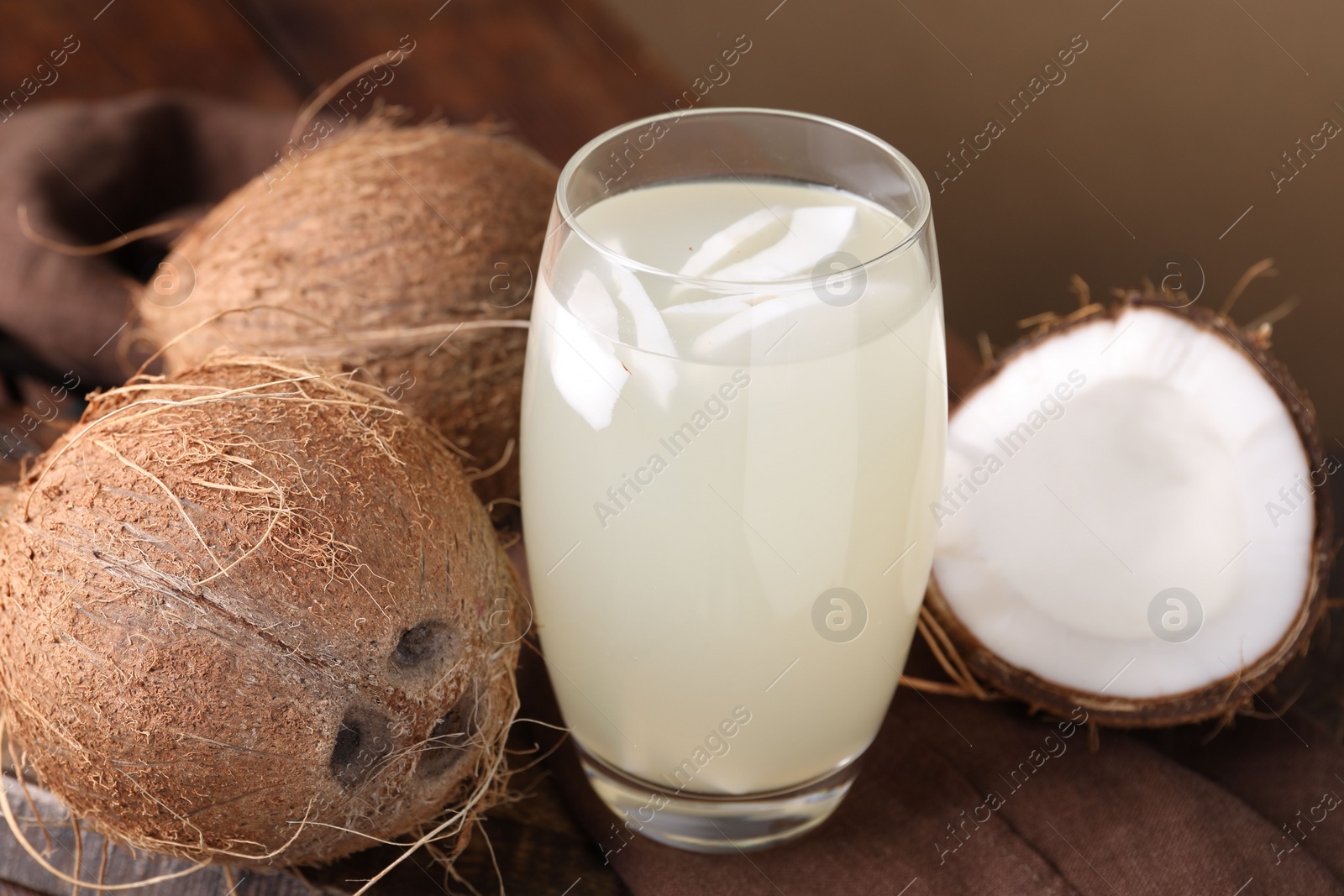 Photo of Glass of coconut water and nuts on wooden table