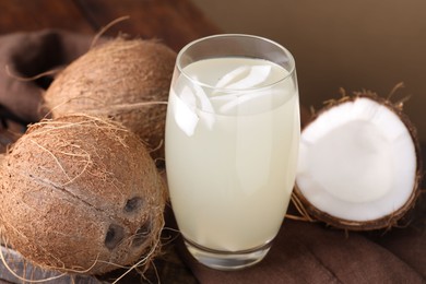 Glass of coconut water and nuts on wooden table