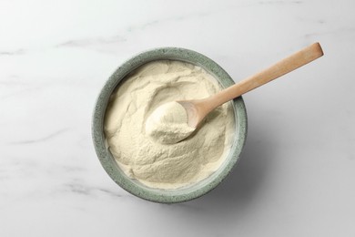 Photo of Bowl and spoon of agar-agar powder on white marble table, top view