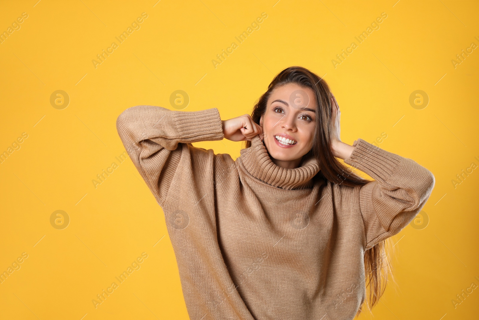 Photo of Young woman in stylish brown sweater on yellow background