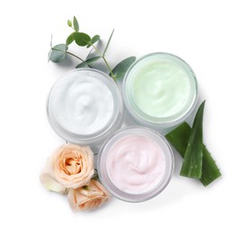 Different body creams with ingredients on white background, top view