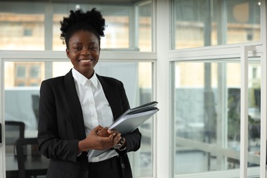 Happy woman with folders in office, space for text. Lawyer, businesswoman, accountant or manager