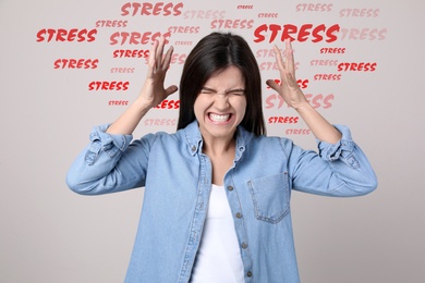 Stressed young woman and text on light background