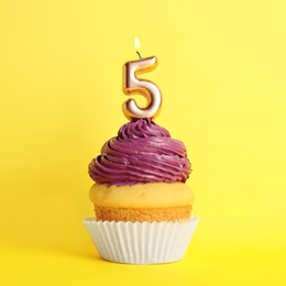 Photo of Birthday cupcake with number five candle on yellow background