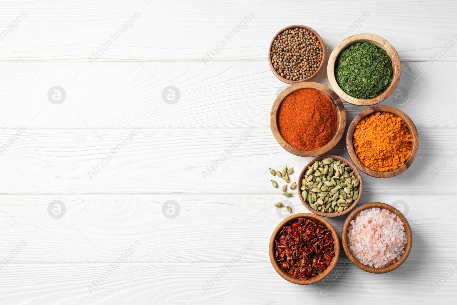 Photo of Bowls with different spices on white wooden table, flat lay. Space for text