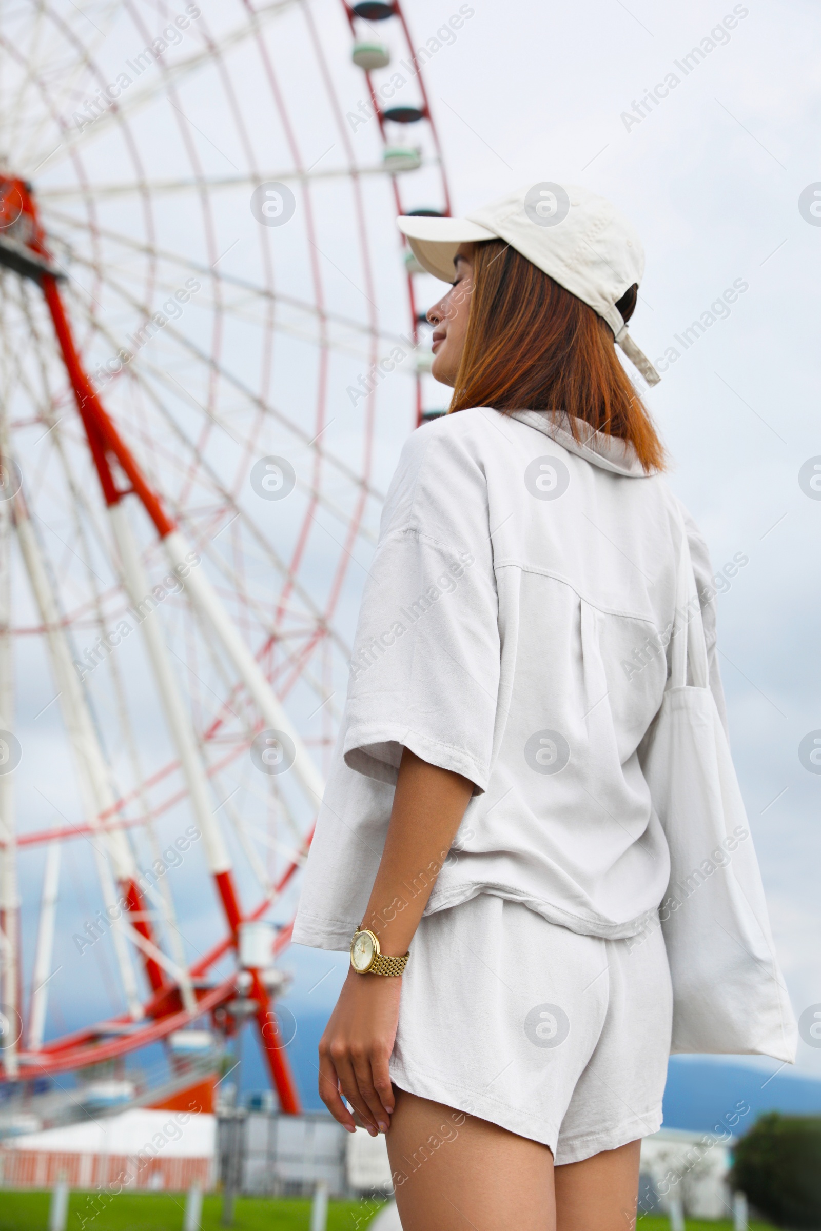 Photo of Beautiful young woman near Ferris wheel outdoors