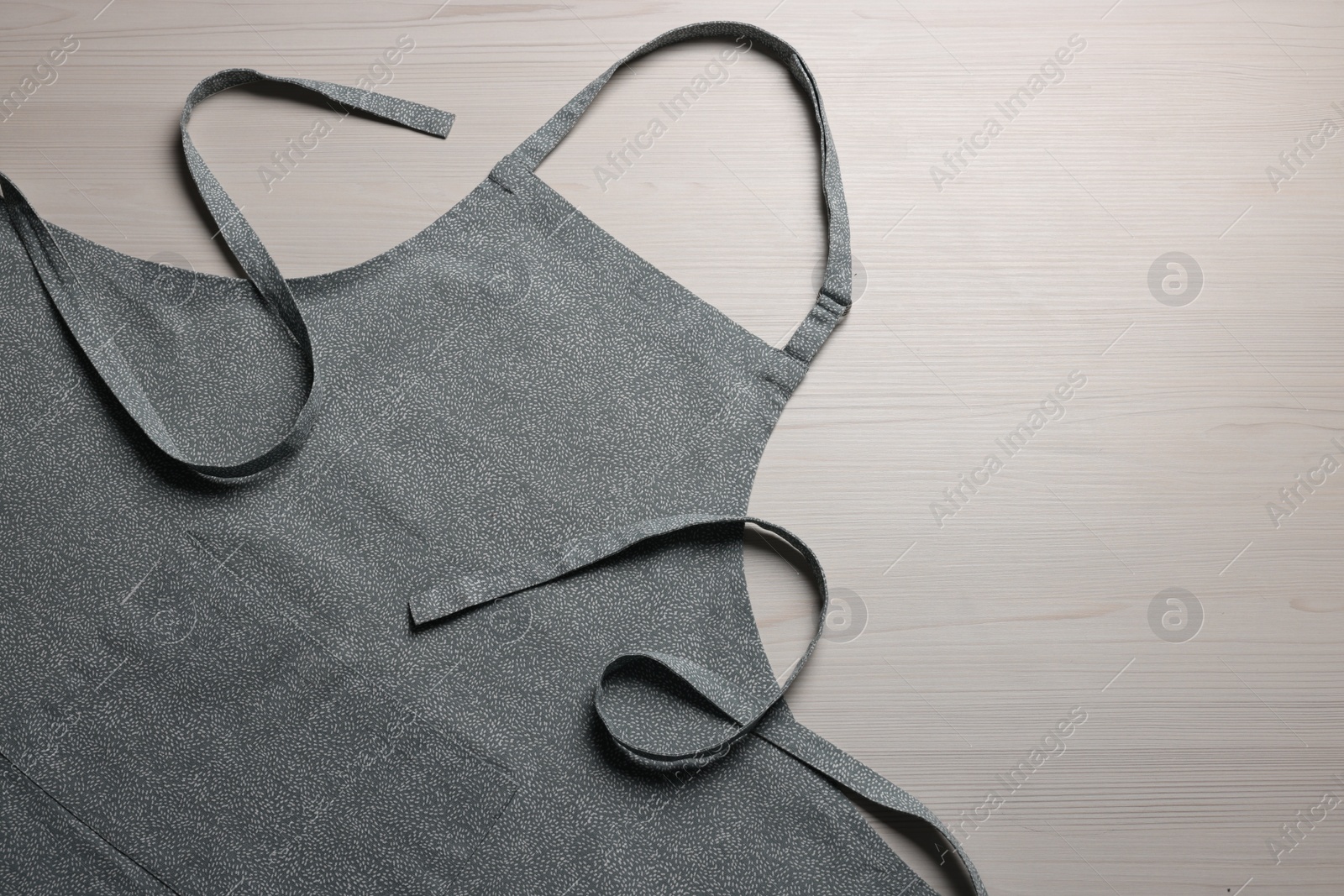 Photo of Stylish apron on white wooden table, top view. Mockup for design