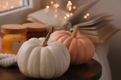 Beautiful pumpkins and scented candles on window sill indoors