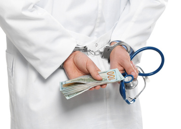 Photo of Doctor in handcuffs with bribe and stethoscope on white background, closeup. Corrupted medicine