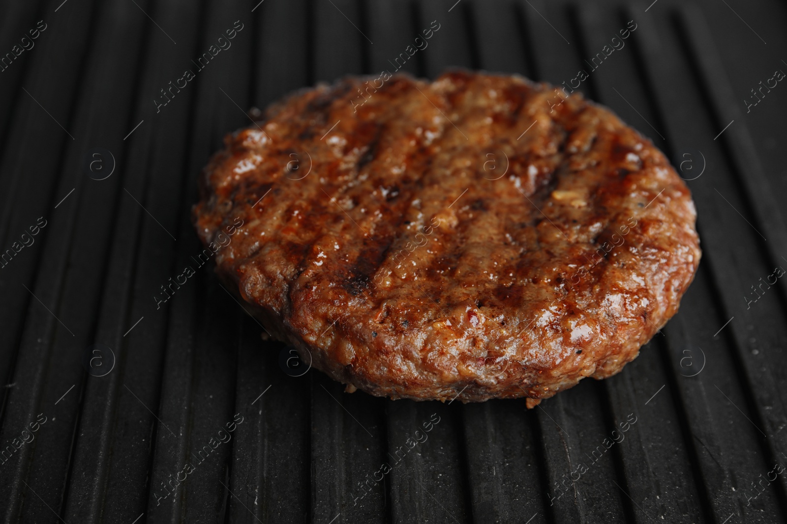 Photo of Prepared meat cutlet for burger on grill, closeup