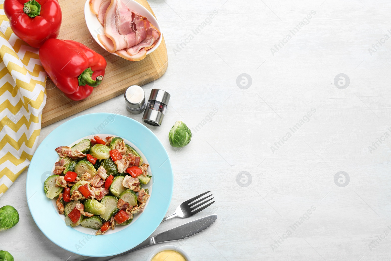 Photo of Delicious cooked Brussels sprouts with bacon served on white table, flat lay. Space for text