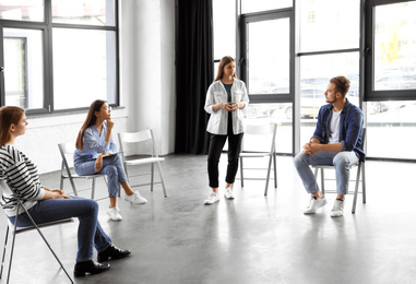 Psychotherapist working with patients in group therapy session indoors