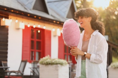 Photo of Smiling woman with cotton candy outdoors on sunny day. Space for text