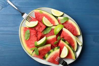Plate with juicy watermelon and lime on blue wooden table, top view