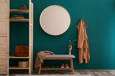 Round mirror on green wall in stylish hallway interior