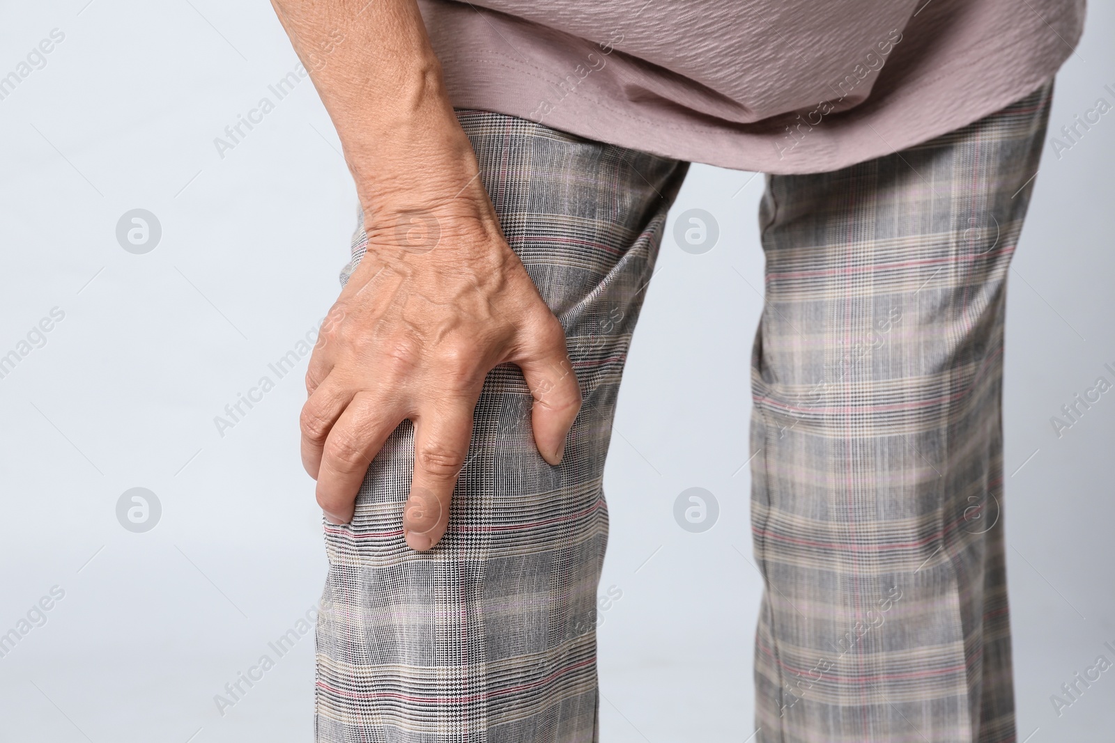 Photo of Senior woman having knee problems on grey background, closeup