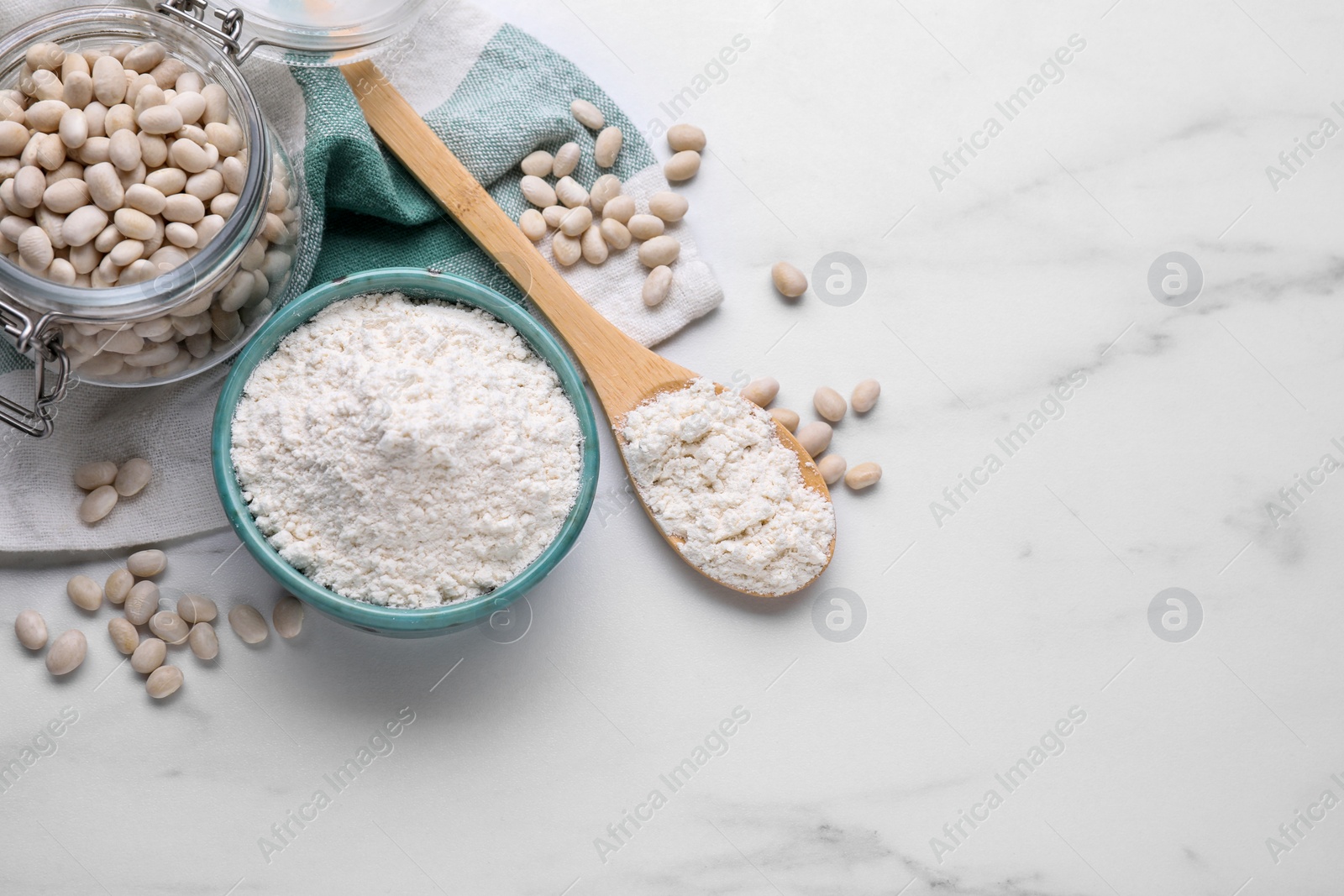 Photo of Bean flour and seeds on white marble table, flat lay. Space for text