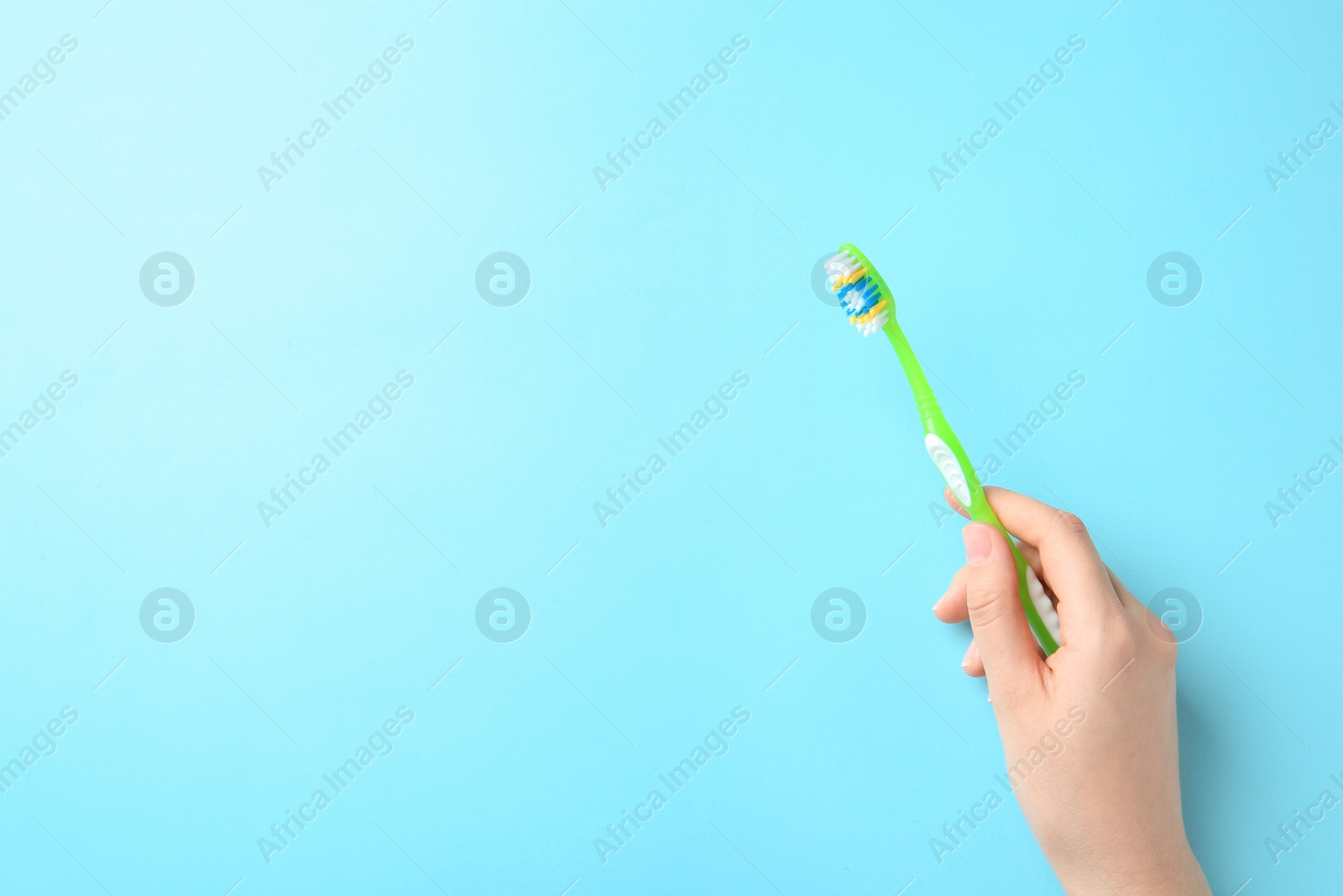 Photo of Woman holding manual toothbrush against color background