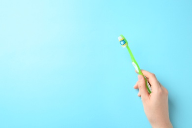 Woman holding manual toothbrush against color background