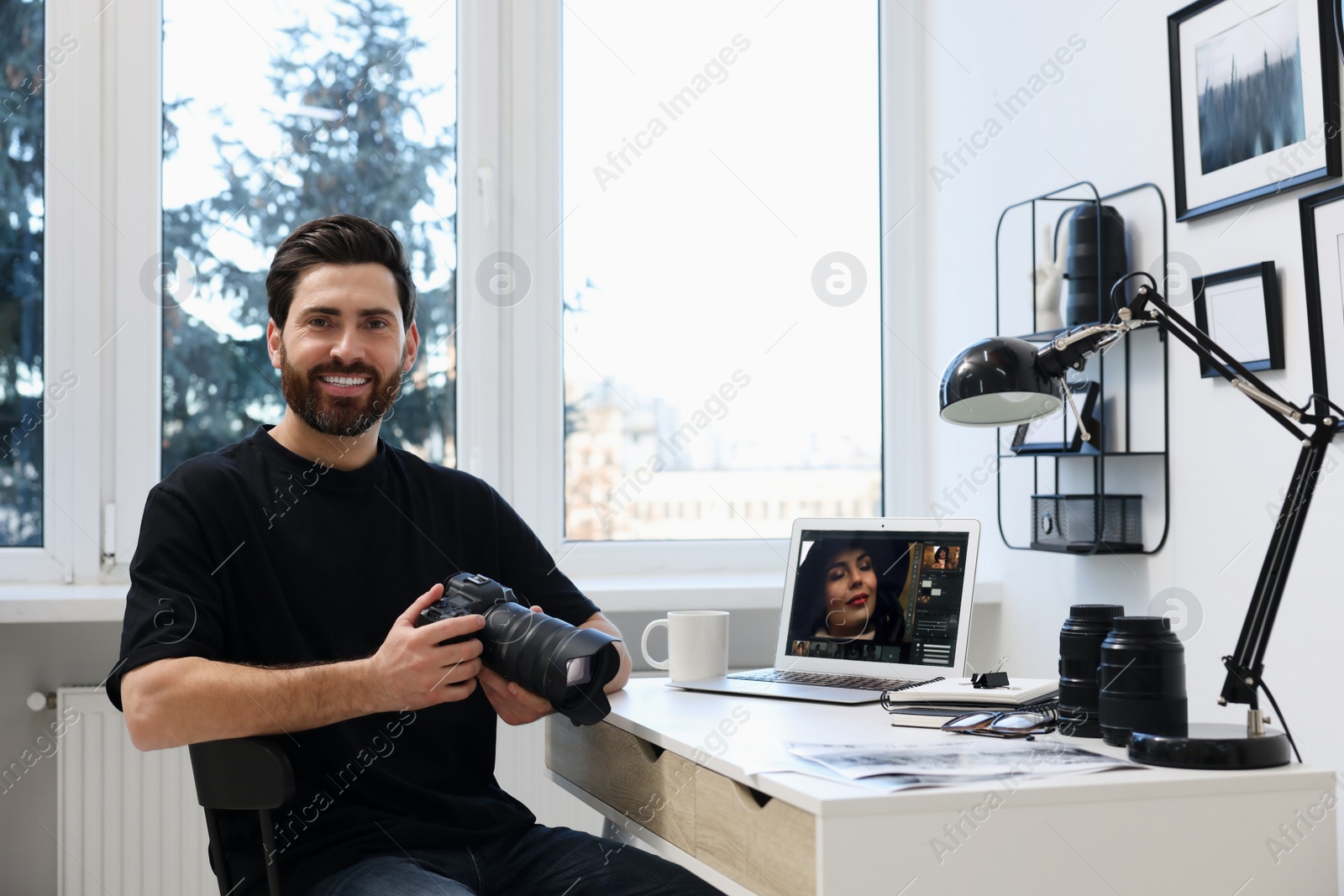 Photo of Professional photographer with digital camera at table in office, space for text