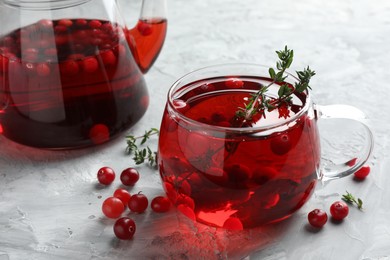 Photo of Delicious cranberry tea with thyme and berries on grey table, closeup