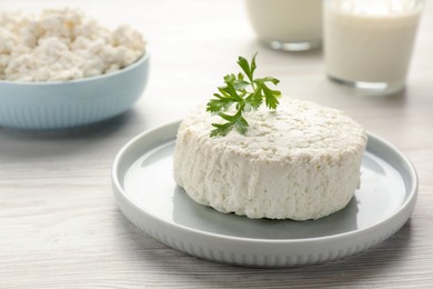 Photo of Delicious fresh cottage cheese with parsley on white wooden table, closeup