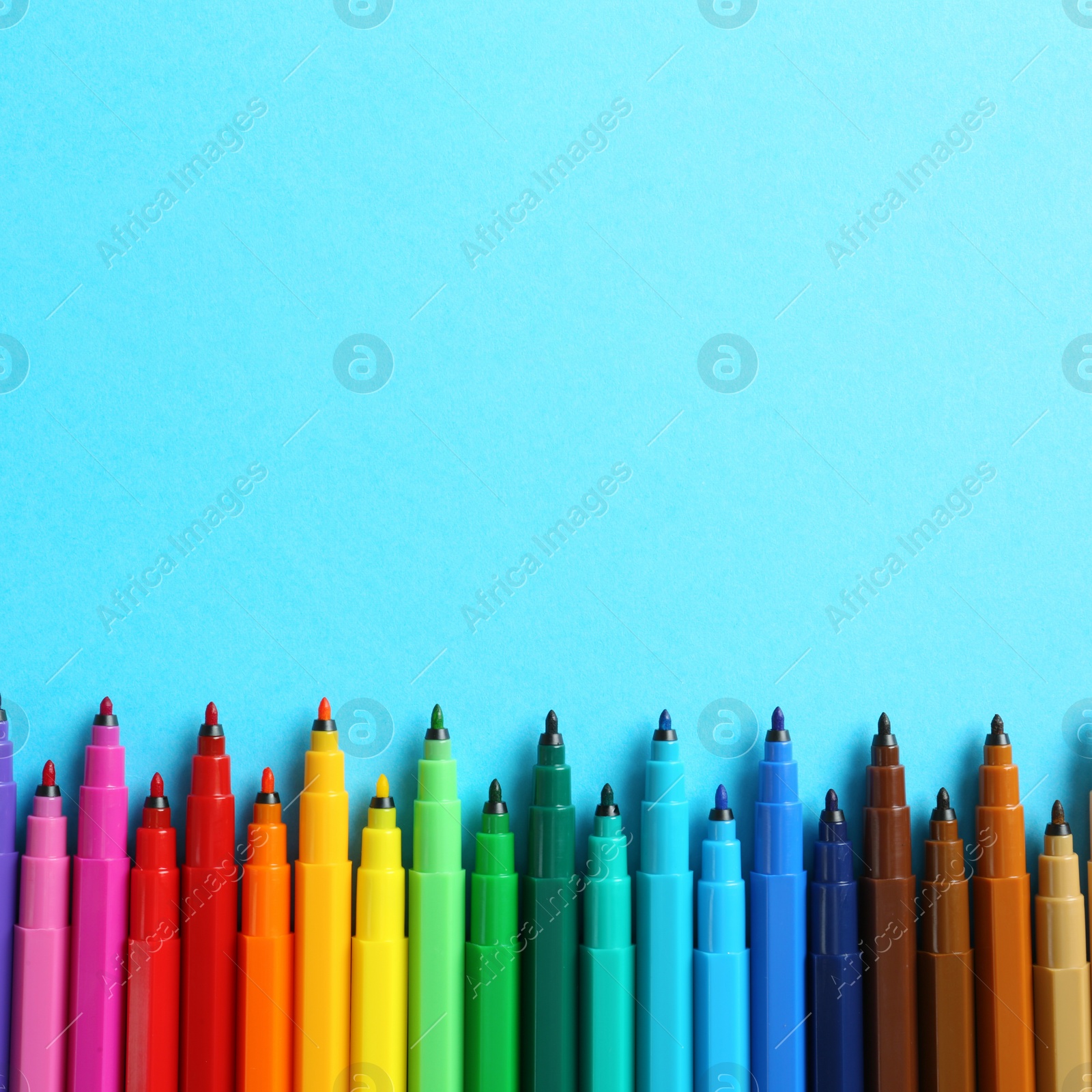 Image of Many colorful markers on light blue background, flat lay. Space for text