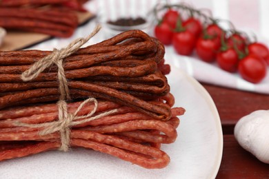 Bundles of delicious kabanosy on wooden table, closeup. Space for text