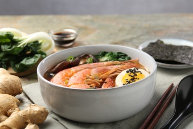 Photo of Delicious ramen with shrimps and egg in bowl served on table, closeup. Noodle soup