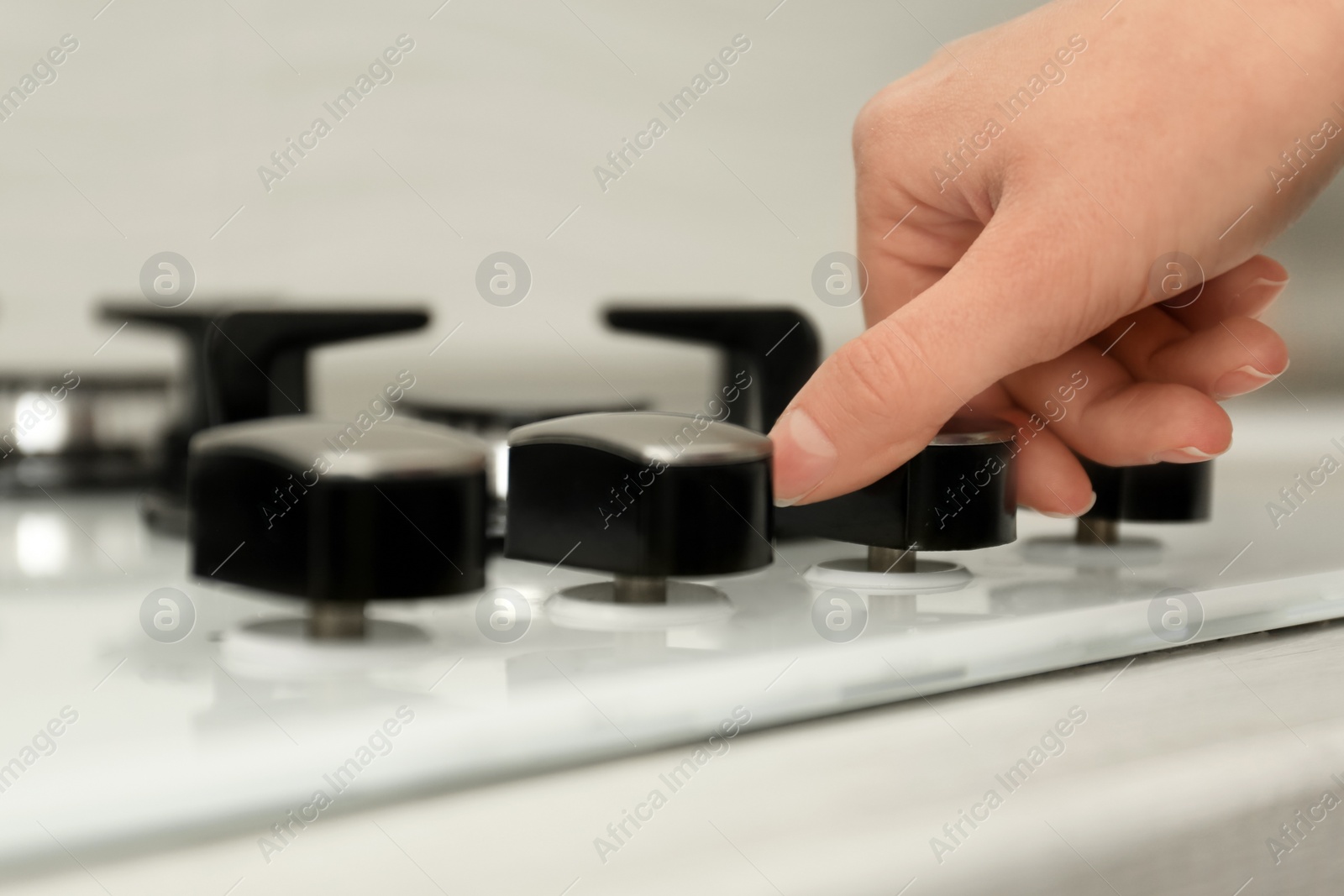 Photo of Woman regulating cooking mode on gas stove panel, closeup