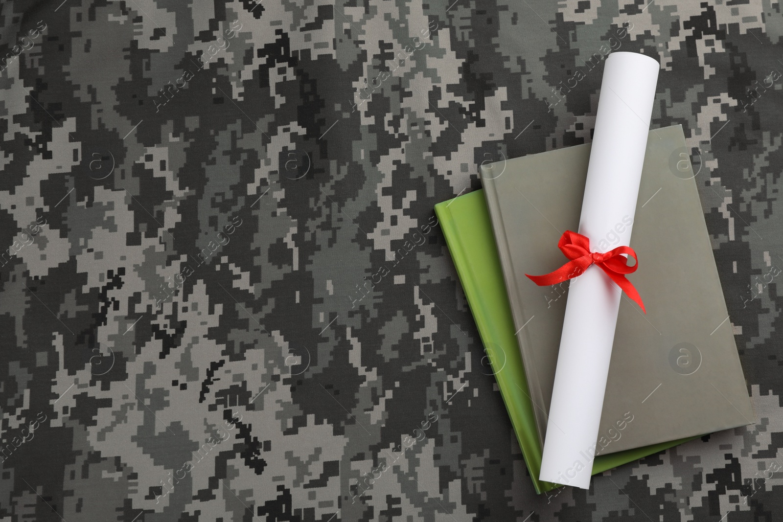 Photo of Books and diploma on camouflage background, top view with space for text. Military education concept