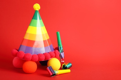 Party cap, blowers and clown noses on red background, space for text