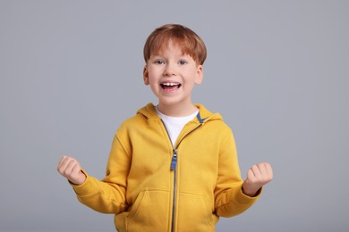Portrait of surprised little boy on grey background