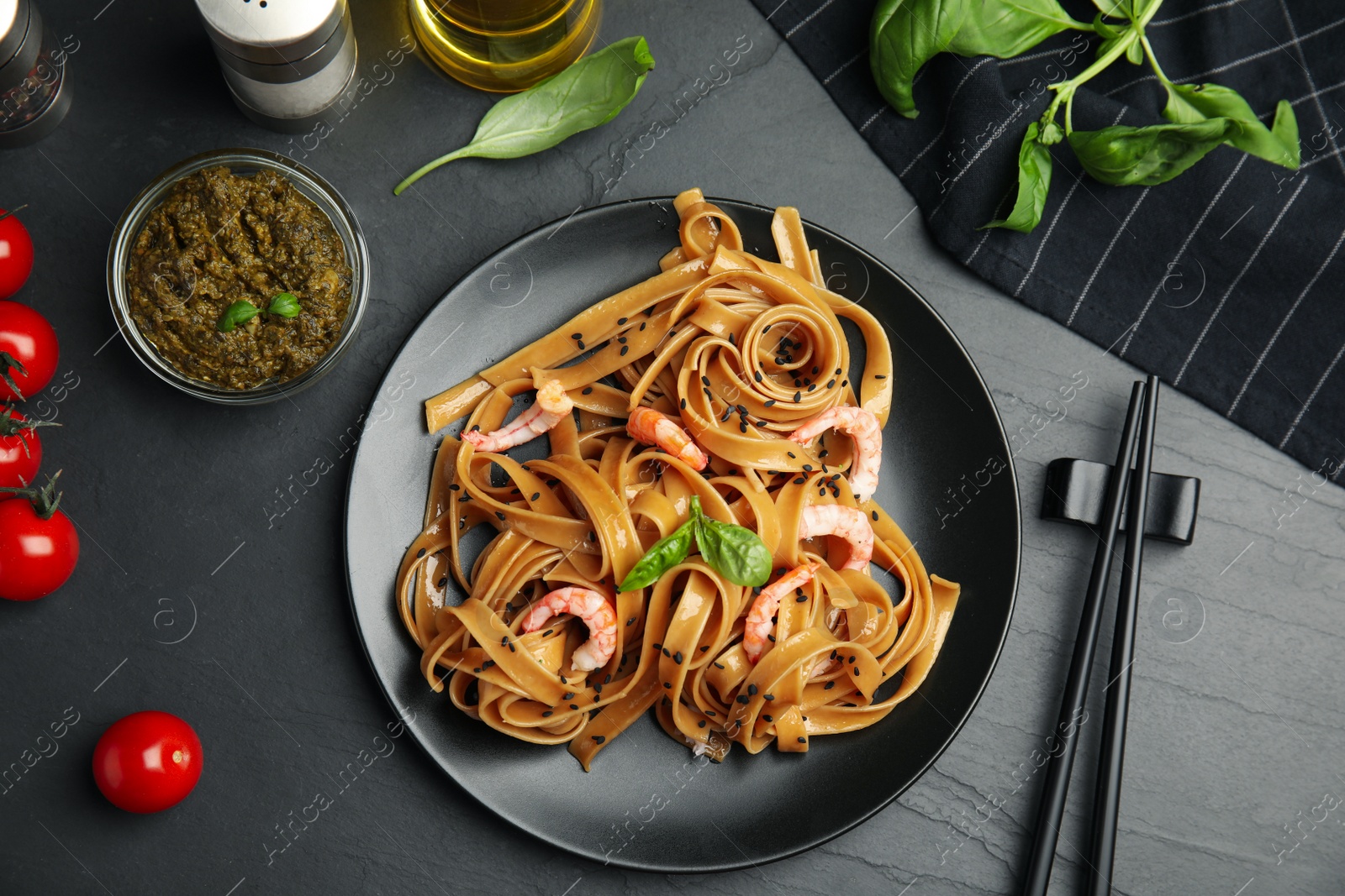 Photo of Tasty buckwheat noodles with shrimps served on black table, flat lay