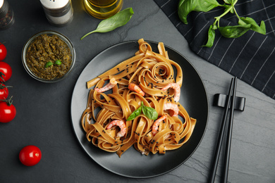 Photo of Tasty buckwheat noodles with shrimps served on black table, flat lay