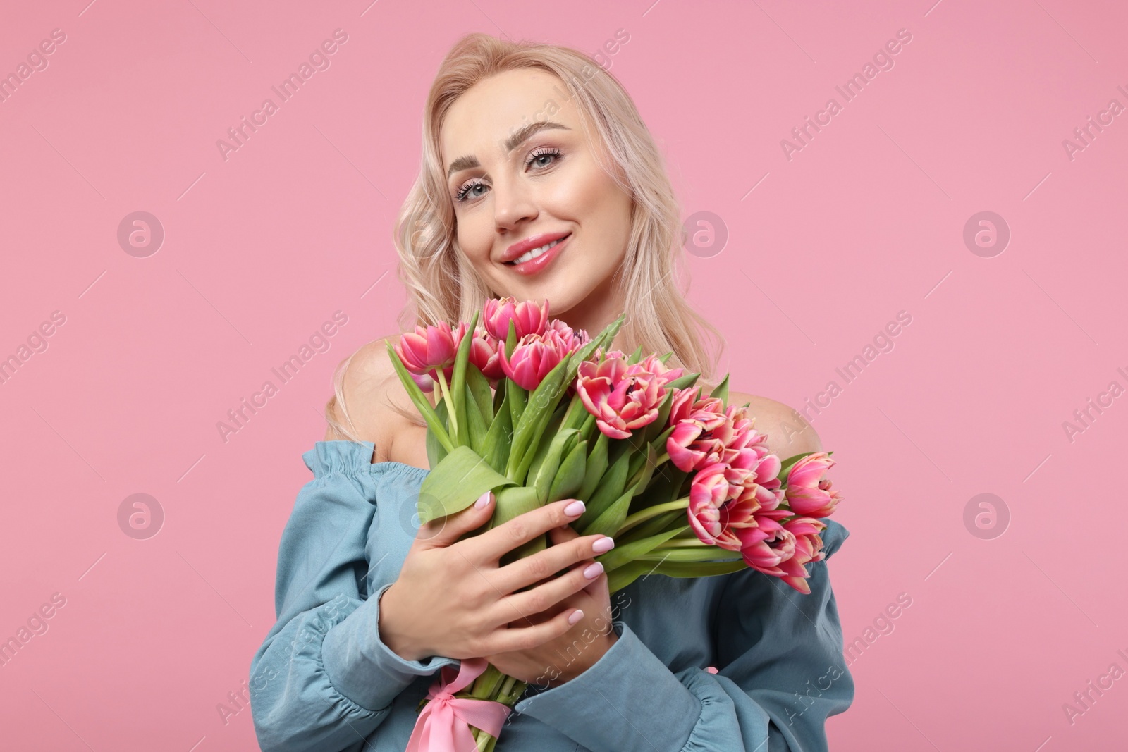 Photo of Happy young woman with beautiful bouquet on dusty pink background