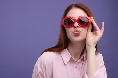 Portrait of beautiful woman in sunglasses on purple background. Space for text