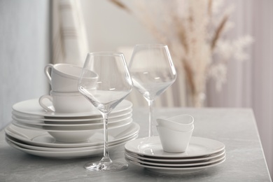 Photo of Set of clean dishware and wineglasses on grey table indoors