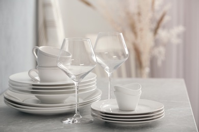 Set of clean dishware and wineglasses on grey table indoors