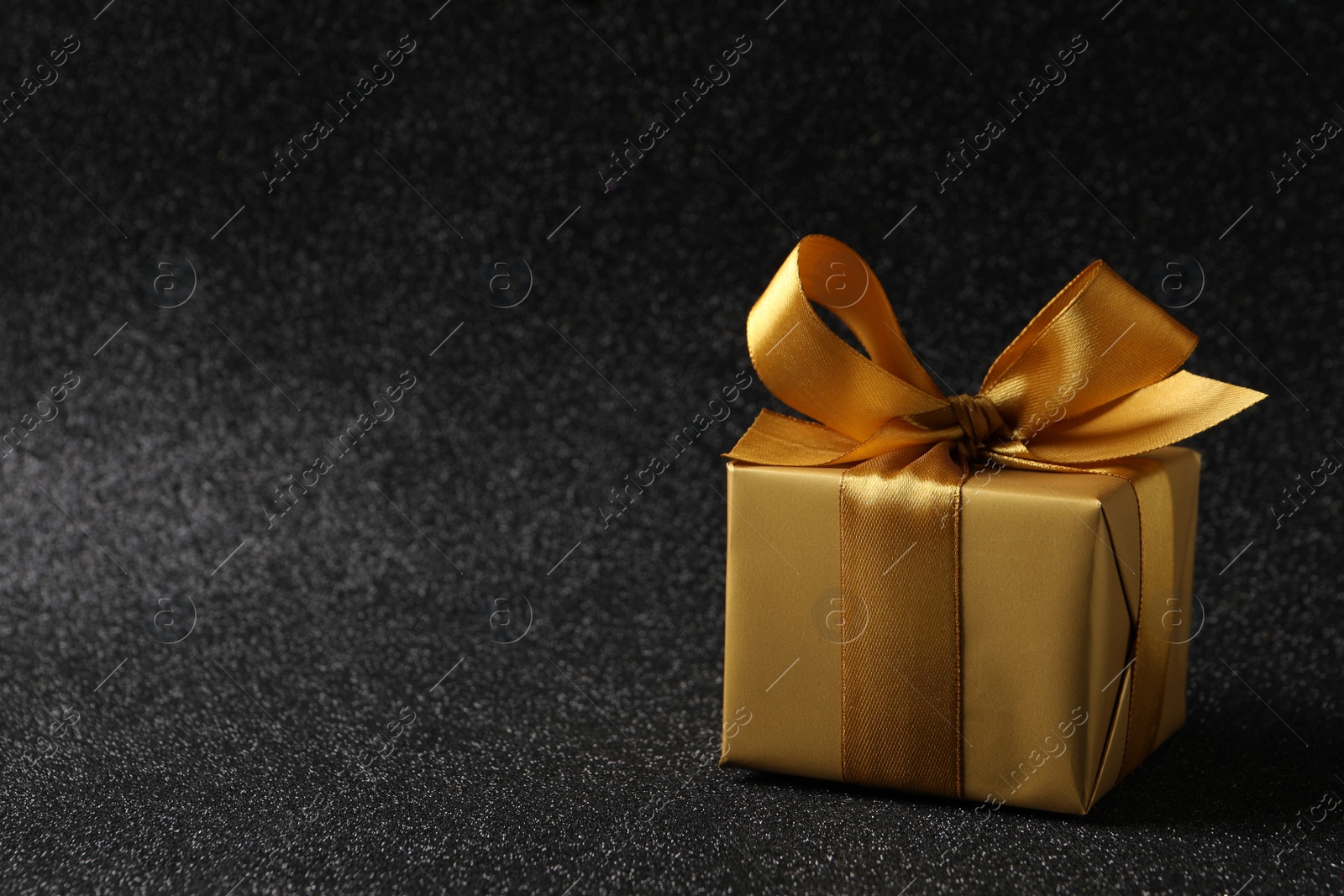 Photo of Beautifully wrapped gift box on black background, space for text