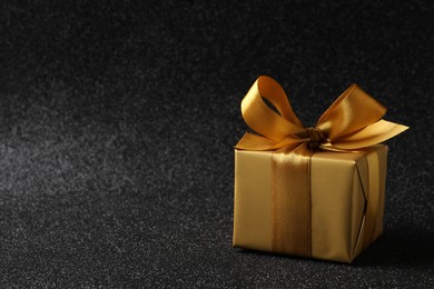 Beautifully wrapped gift box on black background, space for text