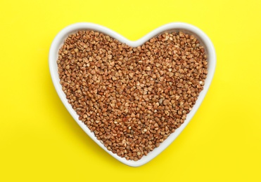 Buckwheat grains on yellow background, top view