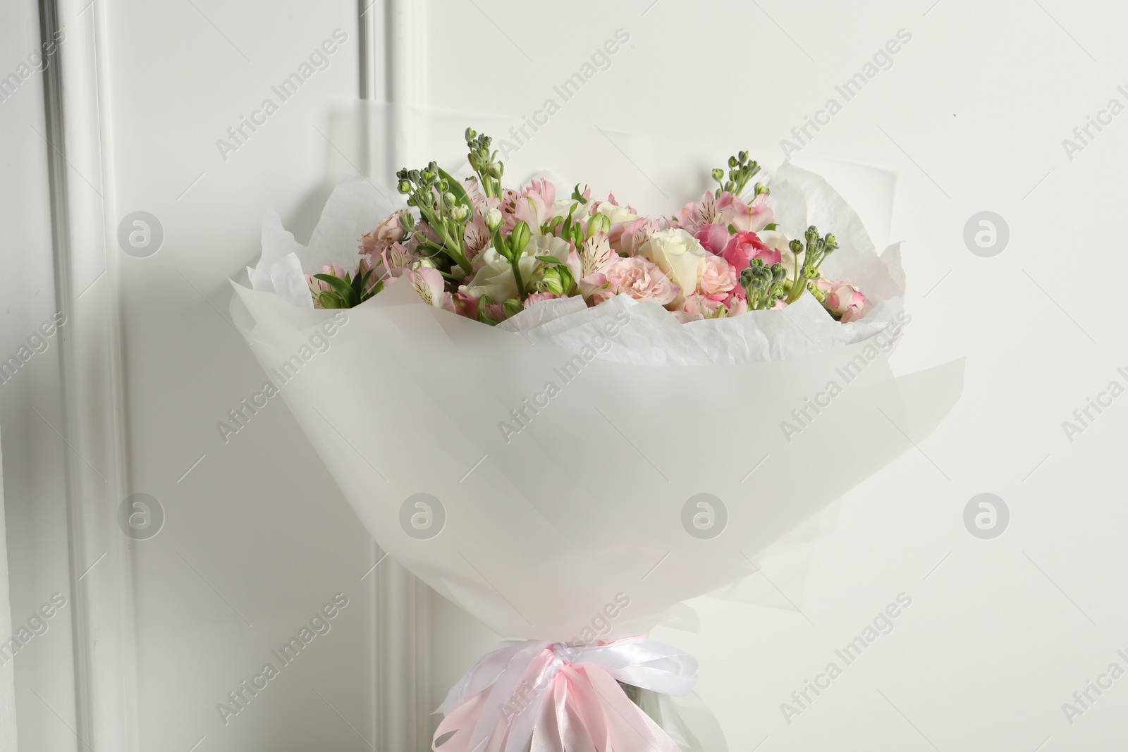 Photo of Beautiful bouquet of fresh flowers near white wall