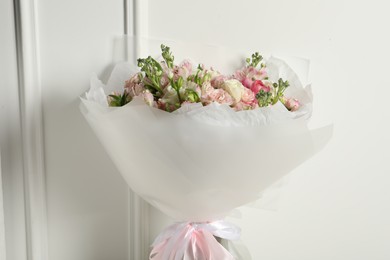 Beautiful bouquet of fresh flowers near white wall