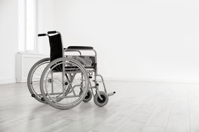 Modern wheelchair in empty room, space for text. Medical equipment