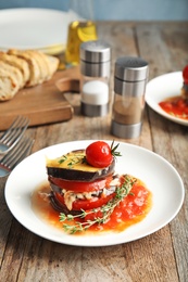 Baked eggplant with tomatoes, cheese and thyme on wooden table