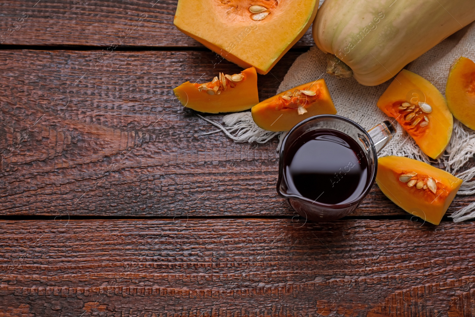 Photo of Flat lay composition with pumpkin seed oil in glass pitcher on wooden table. Space for text