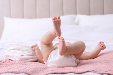 Photo of Little baby and stack of diapers on bed, closeup
