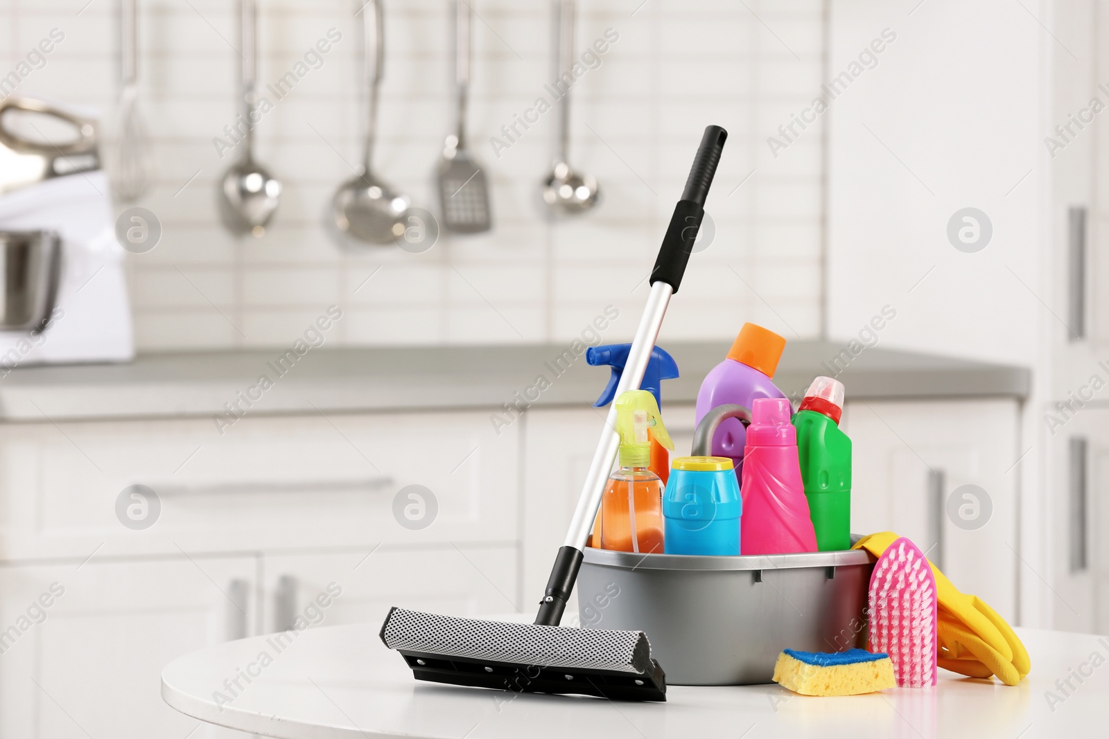 Photo of Set of cleaning supplies on table in kitchen. Space for text